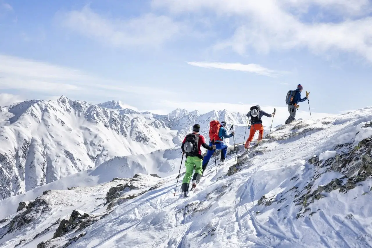 Eine Gruppe von Skifahrern wandert einen verschneiten Berg in der Umgebung hinauf.