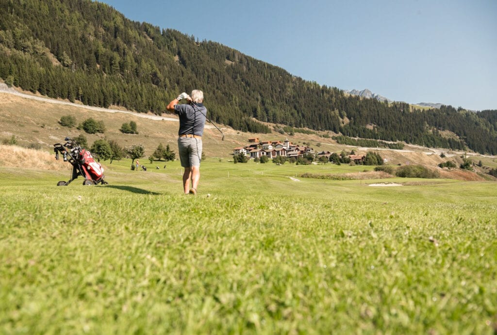 Ein Mann spielt Golf in der bergigen Umgebung.