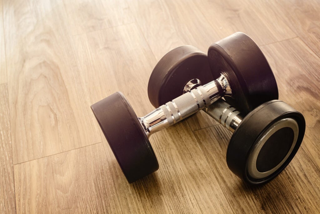 A pair of dumbbells on a wooden floor for a home fitness project.